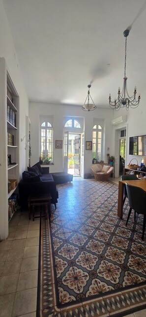 A spacious living area with a patterned floor, a sofa, a dining table, and a chandelier. - Historical apartment in the hart of Jerusalem (Jerusalem)