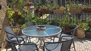 A patio with a round glass table and four chairs, surrounded by potted plants and a tiled floor. - Historical apartment in the hart of Jerusalem (Jerusalem)