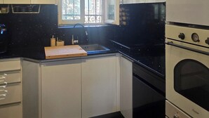 A kitchen with white cabinets, a black countertop, a window, and a double oven. - Historical apartment in the hart of Jerusalem (Jerusalem)