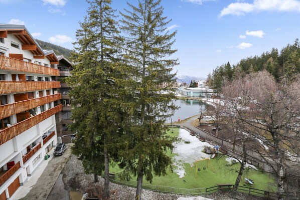 A multi-story hotel with balconies, a lake view, and a playground area.