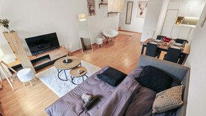 En moderne stue med en stor sofa, et fjernsyn, et spisebord og et køkkenområde.