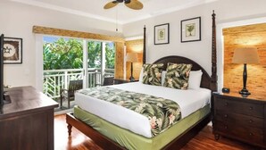 Ein geräumiges Schlafzimmer mit einem großen Bett, einem Deckenventilator und einem Balkon mit Blick auf Grünflächen.