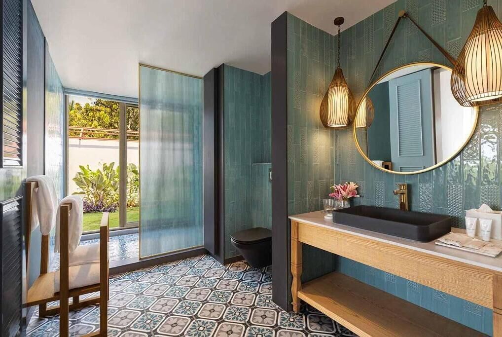 Une salle de bain moderne avec un grand miroir, un lavabo noir et une chaise en bois.
