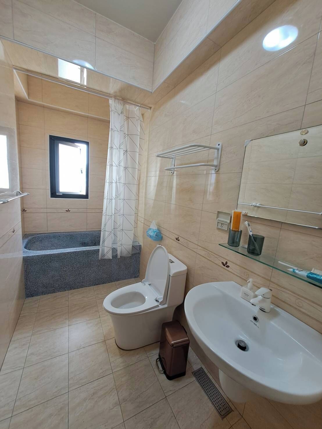 A modern bathroom with a toilet, bidet, sink, and a shower area.