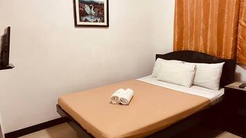 Een net opgemaakt bed met een bruine sprei en witte kussens, een ingelijst foto aan de muur, en een oranje gordijn.