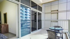 Een moderne hotelkamer met een schuifglasdeur naar een balkon, een klein rond tafeltje en een stoel.