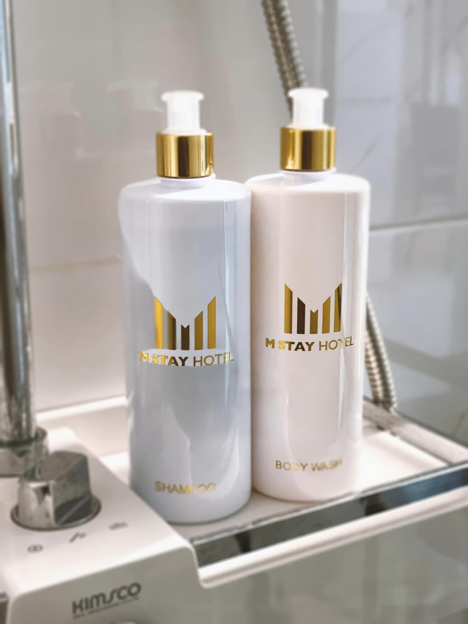 Two bottles of shampoo and body wash on a shower tray.