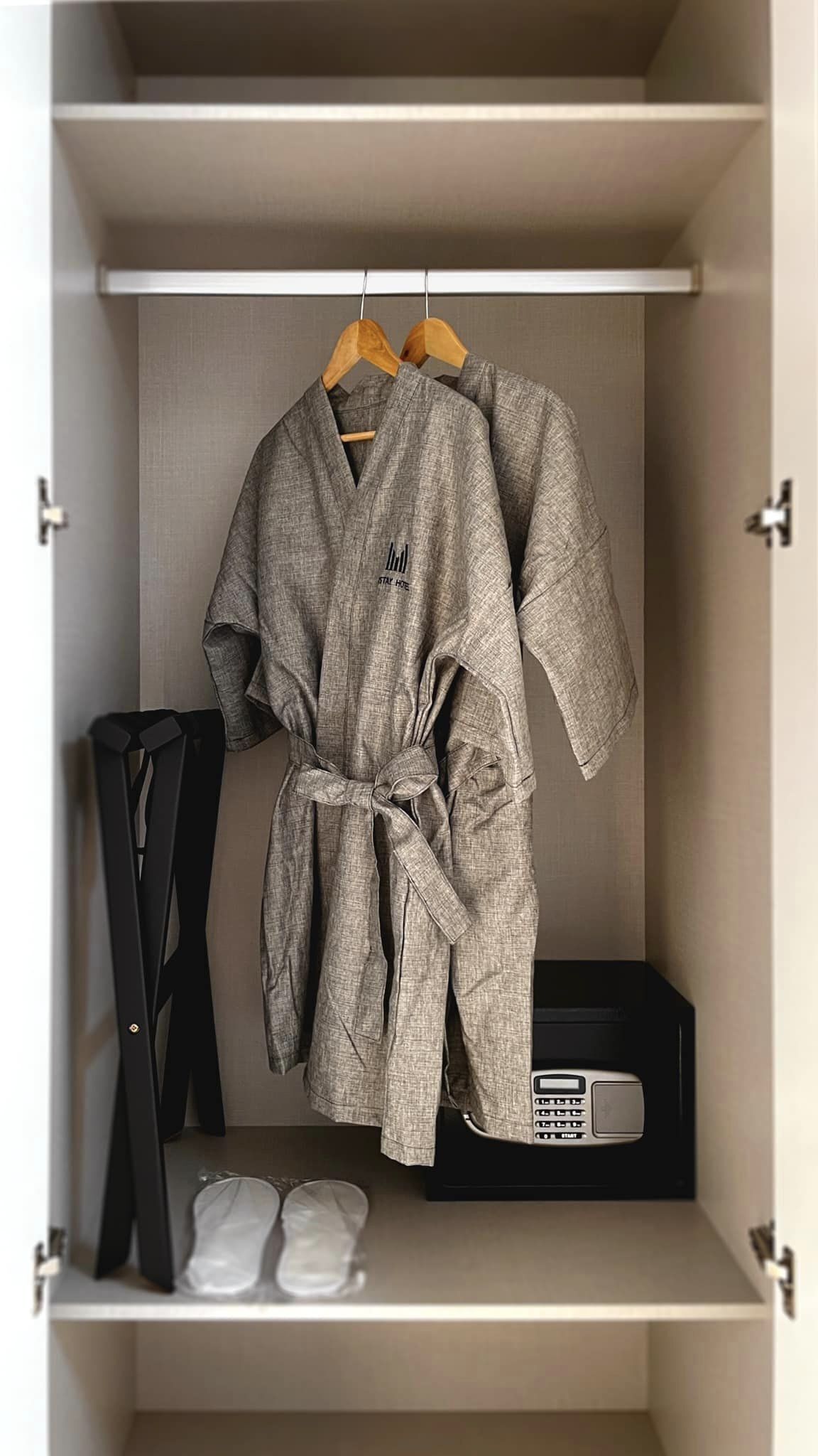 A wardrobe with a grey robe hanging on a wooden hanger.