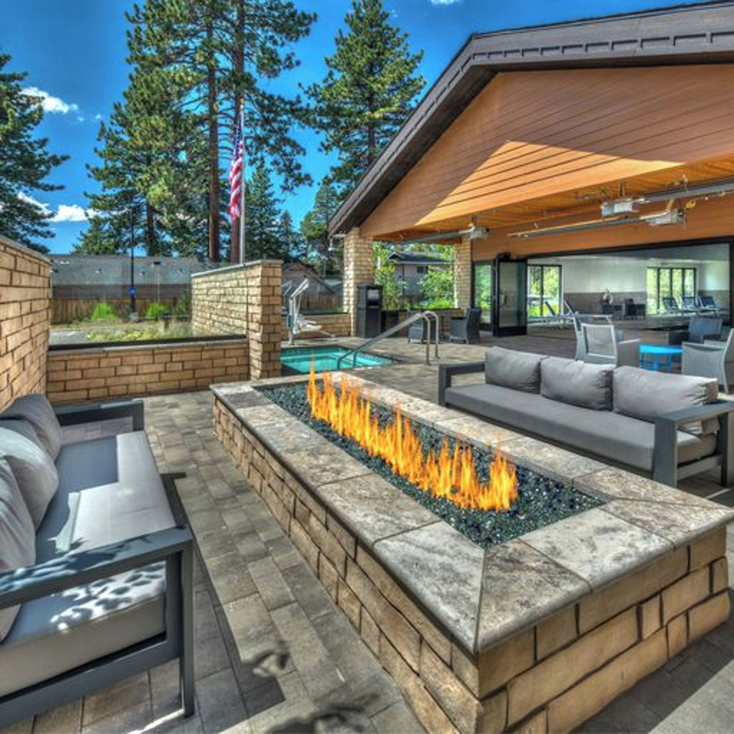 Un patio exterior con una chimenea, asientos y una piscina.
