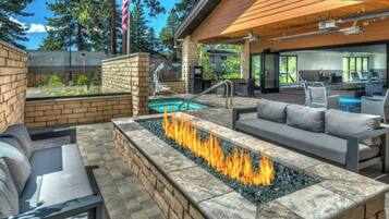 An outdoor patio with a fire feature, seating, and a pool.