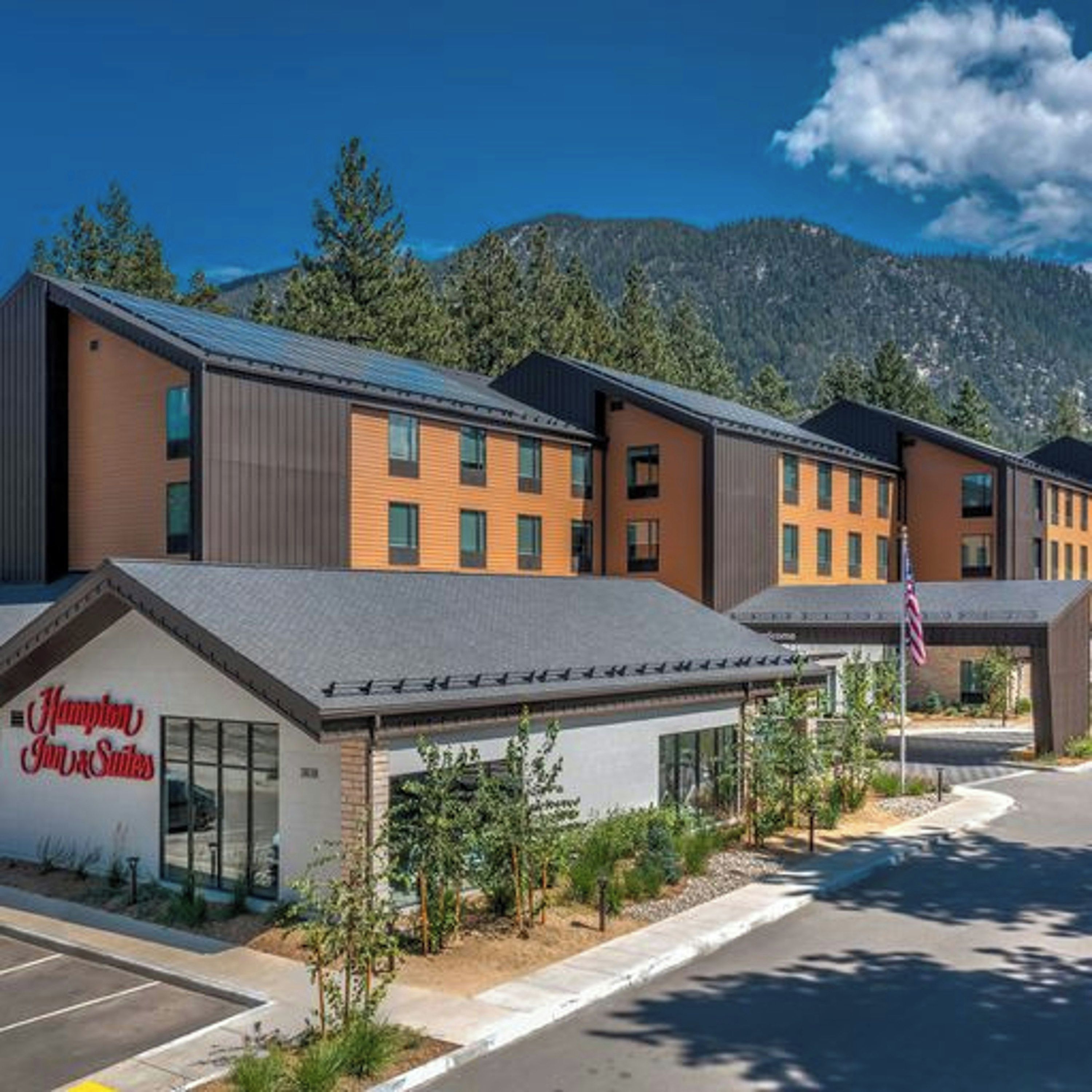 A modern hotel with a flat roof, multiple windows, and a sign for Hampton Inn Suites.