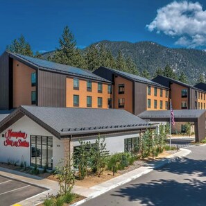 A modern hotel with a flat roof, multiple windows, and a sign for Hampton Inn Suites.