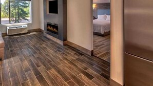 A modern hotel room with a fireplace, a bed, and a large window. - Hampton Inn and Suites South Lake Tahoe (South Lake Tahoe)