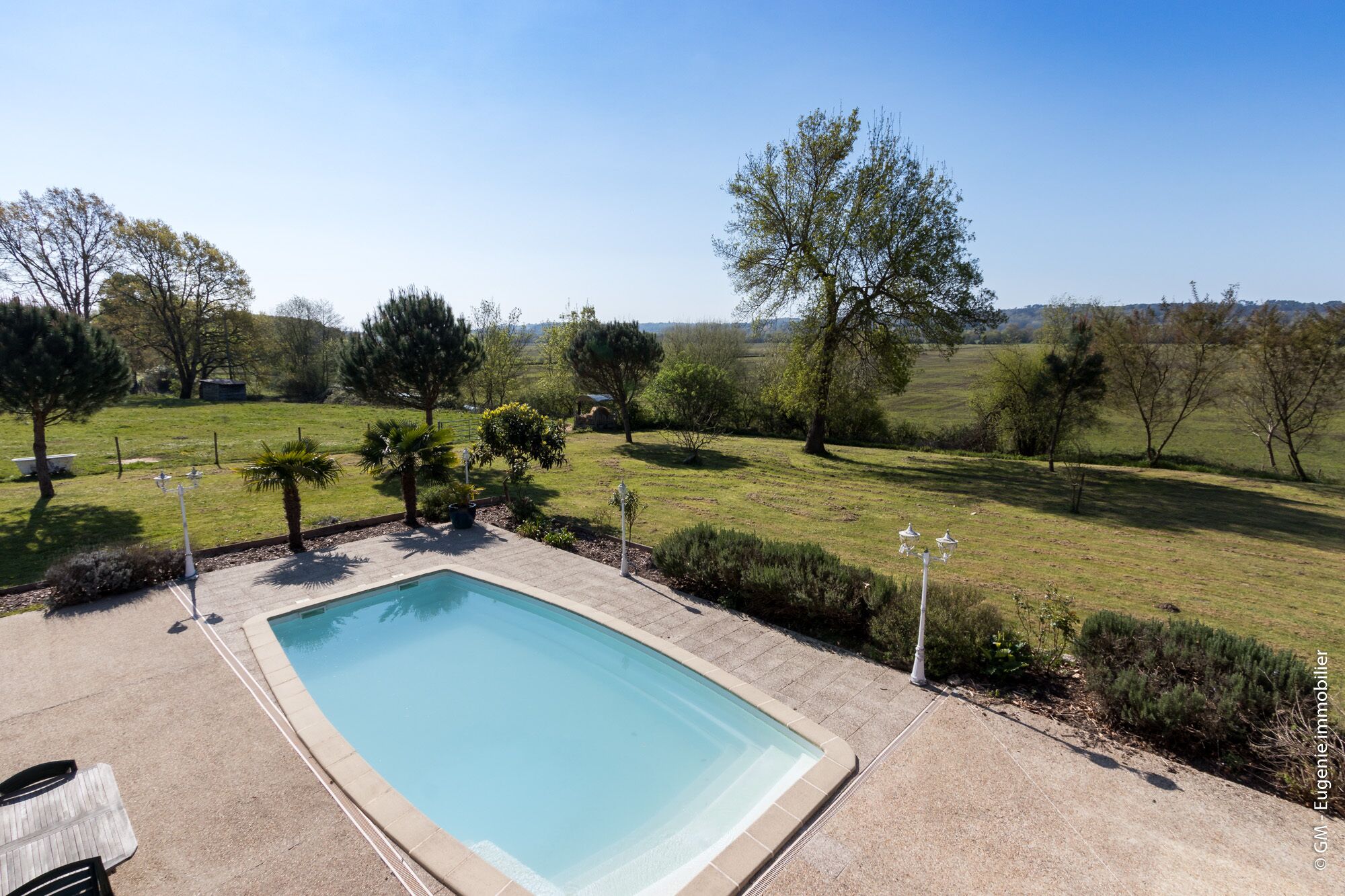 A rectangular swimming pool with a tiled edge, surrounded by a concrete deck.