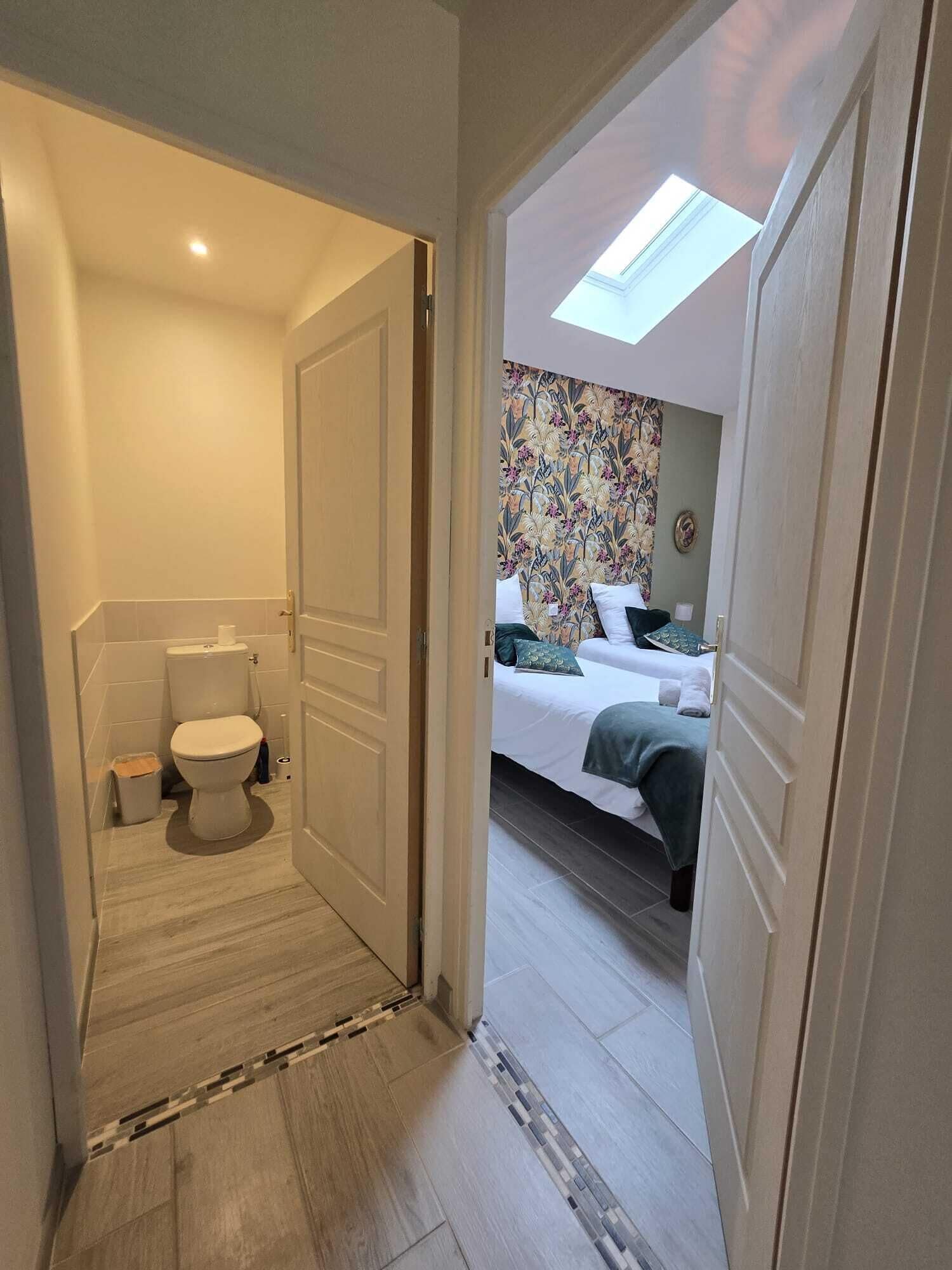 Una habitación de hotel con baño, cama con cabecera de estampado floral y tragaluz.