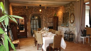 A dining area with a stone wall, a wooden cabinet, and a table set for six. - Domaine Castetbieilh (Tercis-les-Bains)