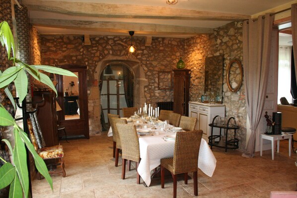 Un comedor con pared de piedra, un armario de madera y una mesa preparada para seis personas.