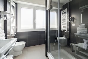A modern bathroom with a glass shower enclosure, a toilet, a sink, and a bidet.