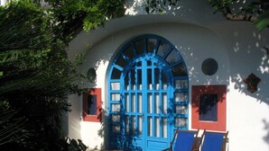 A white building with a blue arched door and two blue chairs outside. - Dimora Coloniale B&B (Forio)