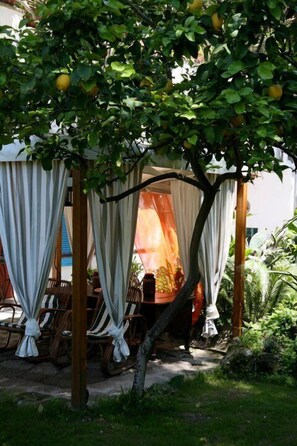 A covered outdoor seating area with striped canopies and wooden chairs.