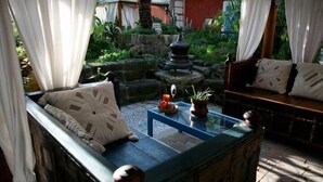 A cozy outdoor seating area with a sofa and a small table, surrounded by lush greenery and a stone fountain. - Dimora Coloniale B&B (Forio)