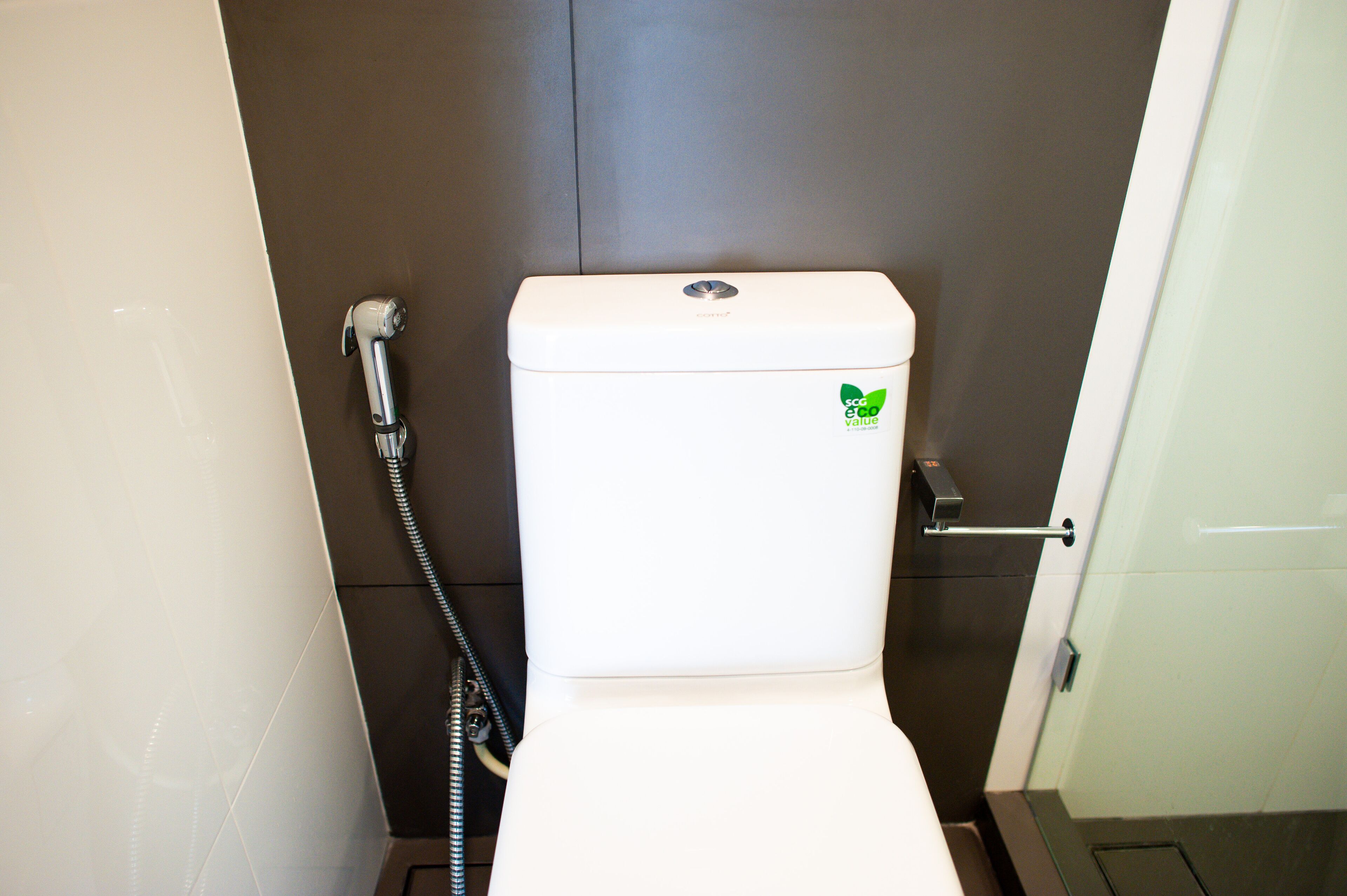 A compact, modern bathroom with a white toilet, a visible water heater, and a door handle.