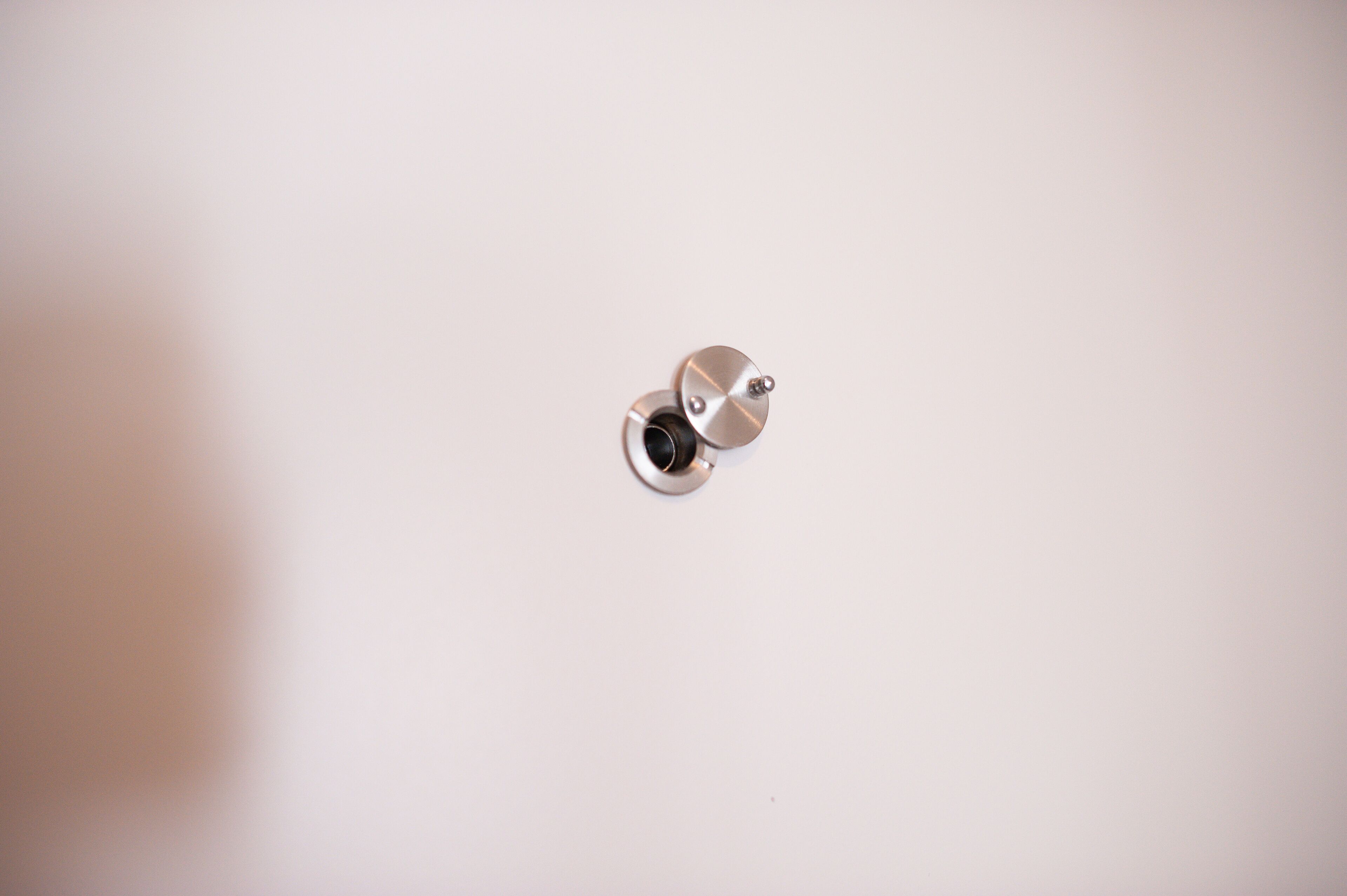A metallic object, possibly a part of a fixture, on a plain white background.