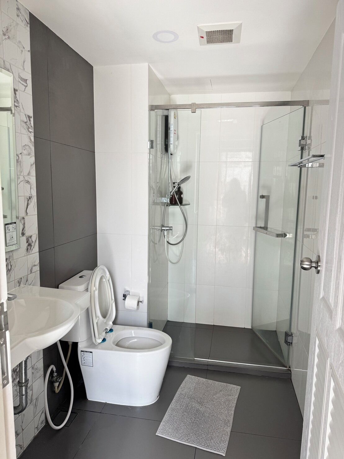 Egy modern fürőszoba, amelyben WC, mosdókagyló és zuhanyzó található.