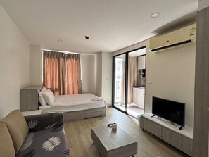 A modern hotel room with a bed, sofa, TV, and a sliding glass door to the balcony. - I'm Chinatown Residence (Bangkok)