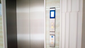 An elevator with a control panel featuring a wheelchair accessibility symbol, a no smoking sign, and a button with a clock symbol. - I'm Chinatown Residence (Bangkok)