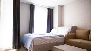 A modern hotel room with a bed, a sofa, and a wooden coffee table. - I'm Chinatown Residence (Bangkok)