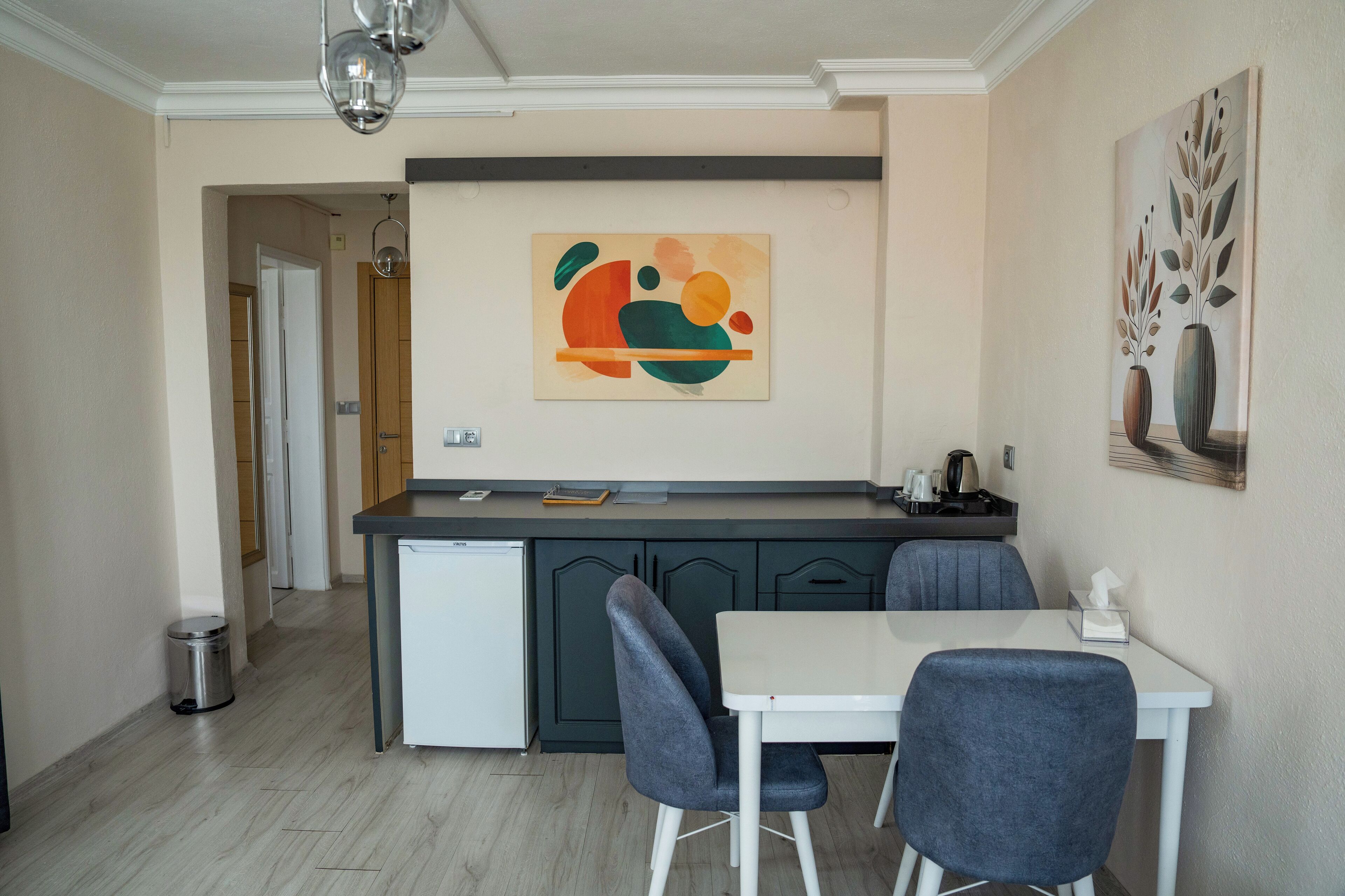 Una cocina moderna con una isla central, sillas grises y una mesa blanca.