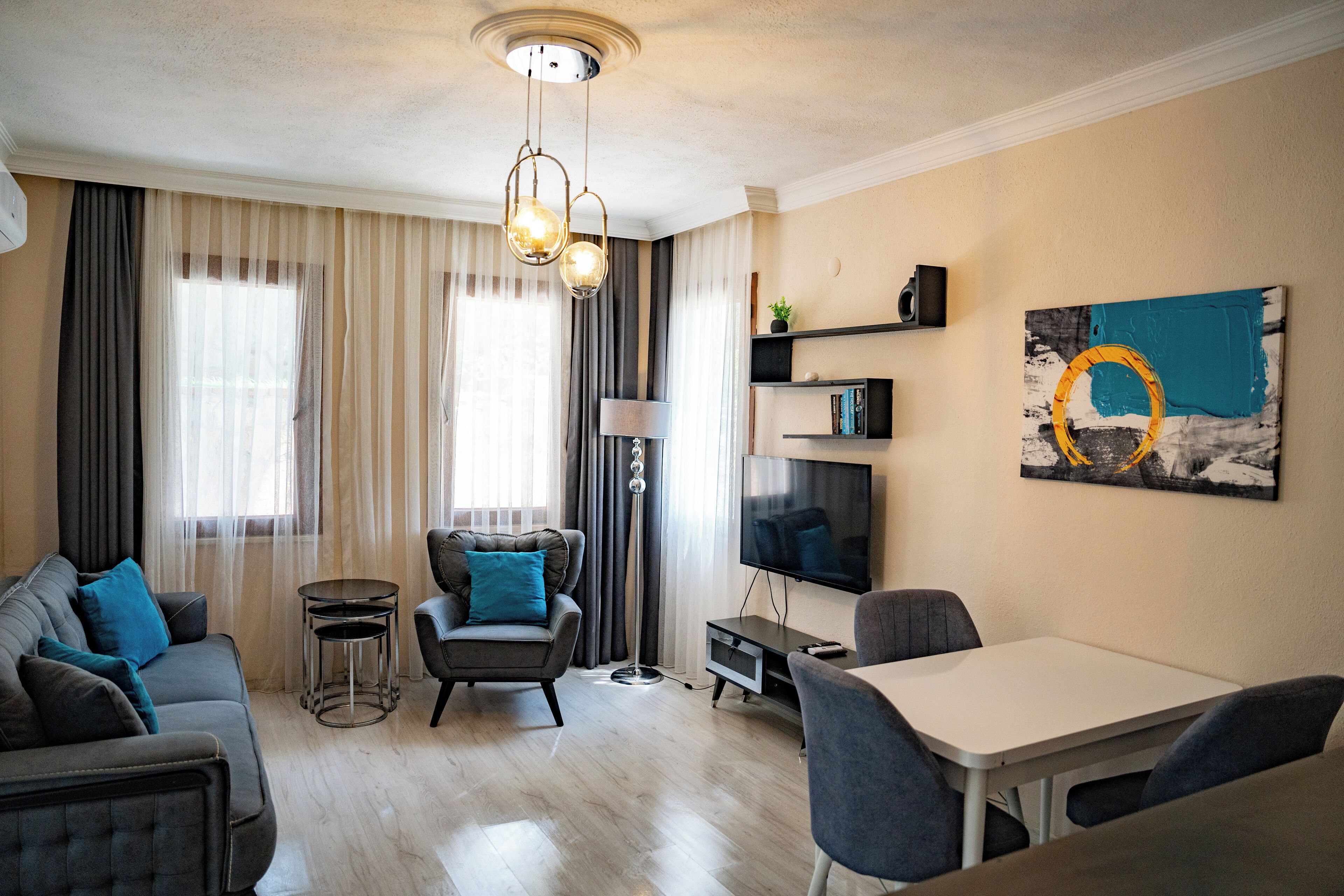 Una sala moderna con sofá, sillón, mesa de comedor y televisor.