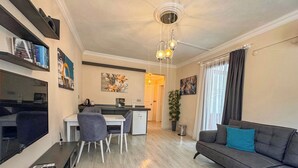 Uma sala de estar moderna com um sofá, um espaço de jantar com mesa e cadeiras, uma televisão e obras de arte nas paredes.