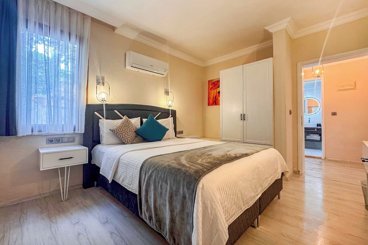 Un dormitorio con cama, mesitas de noche, armario y aire acondicionado.
