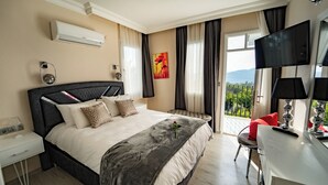 Quarto de hotel moderno com uma cama grande, uma escrivaninha e uma televisão.