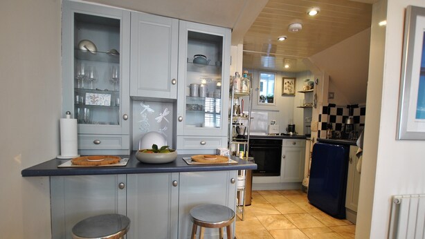 A kitchen with a central island, stools, and a refrigerator. - Oyster Cottage- relaxing retreat by the sea (Saint Monans)