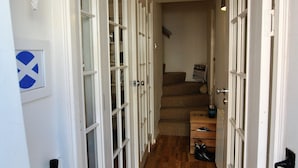A narrow hallway with wooden flooring and white doors leading to rooms. - Oyster Cottage- relaxing retreat by the sea (Saint Monans)