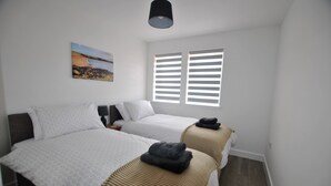 Un dormitorio con dos camas, un cuadro en la pared y una ventana con persianas.