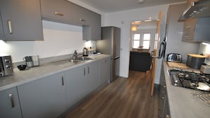 Una cocina moderna con armarios grises, electrodomésticos de acero inoxidable y suelo de madera.