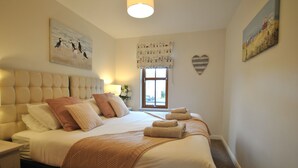 A bedroom with a large bed, a window with a view, and a heart-shaped decoration on the wall.