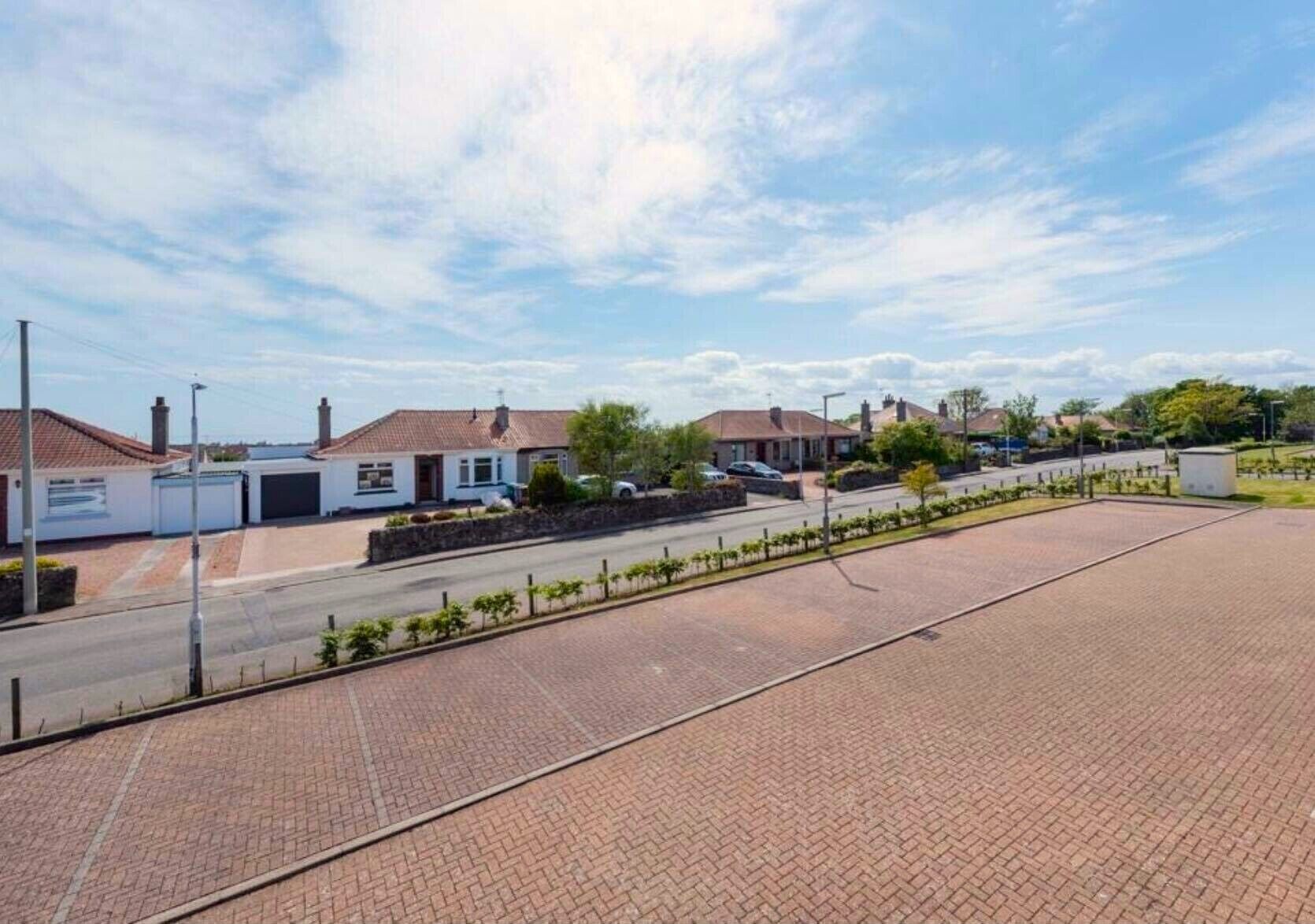 A residential area with houses, a paved road, and a clear sky.