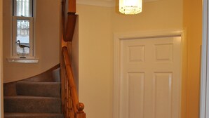 A staircase with carpeted steps and wooden handrails, leading to a white door with a window above it.