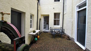 A courtyard with a brick floor, a table with chairs, and a small garden area with a table and chairs. - Gyles Apartment - harbourfront studio, Pittenweem (Pittenweem)