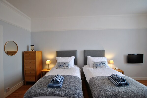 A hotel room with two beds, a wooden dresser, a TV, and a mirror. - Gyles Apartment - harbourfront studio, Pittenweem (Pittenweem)