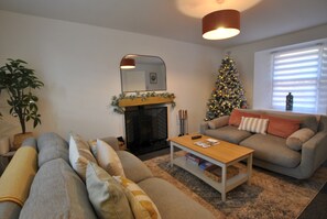A living room with a fireplace, a Christmas tree, a sofa, and a coffee table.