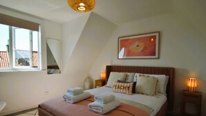 Une chambre avec un grand lit, une fenêtre et un tableau accroché au mur.