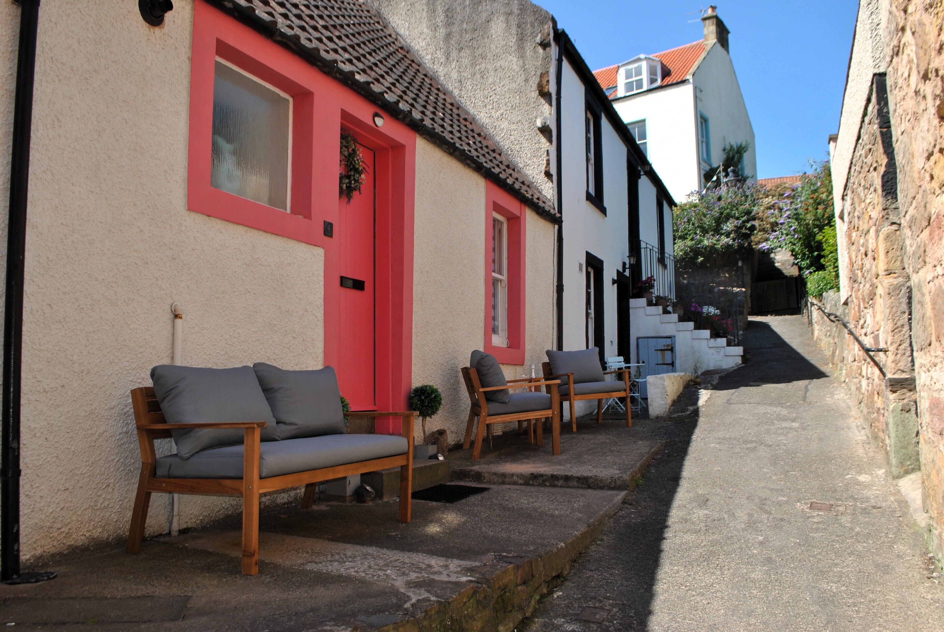 A narrow street with a row of traditional buildings, a bench, and a staircase leading to a higher level.