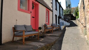 Une rue étroite bordée de bâtiments traditionnels, avec un banc et un escalier menant à un niveau supérieur.