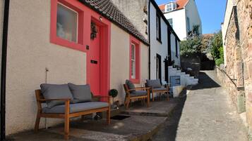 A narrow street with a row of traditional buildings, a bench, and a staircase leading to a higher level.